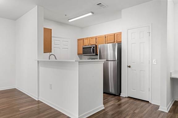 A kitchen with white walls and wooden floors.