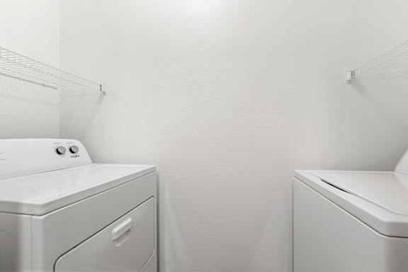 Two white front load washing machines in a laundry room.