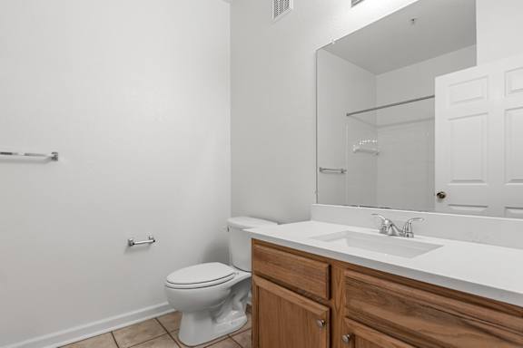 A white toilet sits in a bathroom next to a sink.