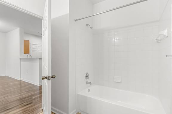 A white bathroom with a tub and a doorway to another room.