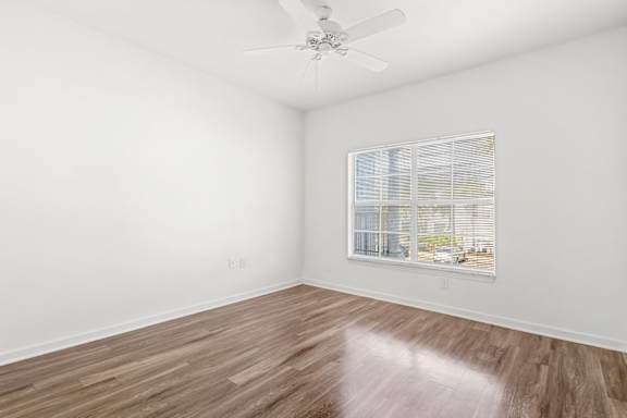 A room with a ceiling fan and a window with blinds.