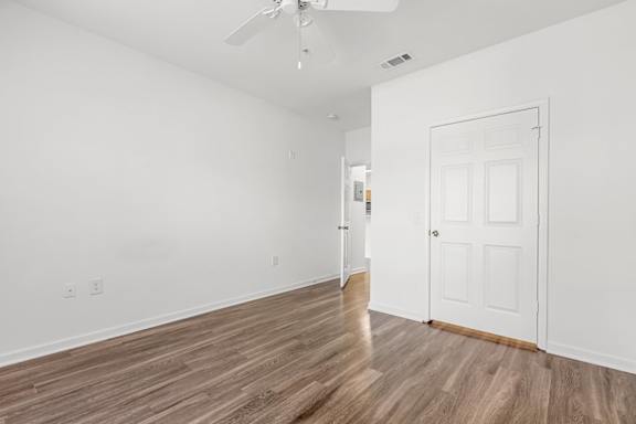 A room with a white door and a ceiling fan.
