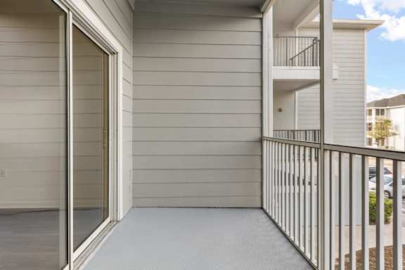A balcony with a metal railing and a glass door leading to a building.