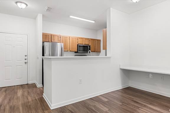 A kitchen with white walls and wooden cabinets.