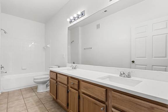 A white bathroom with a toilet, sink, and mirror.