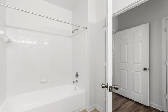 A white bathroom with a tub and a door.