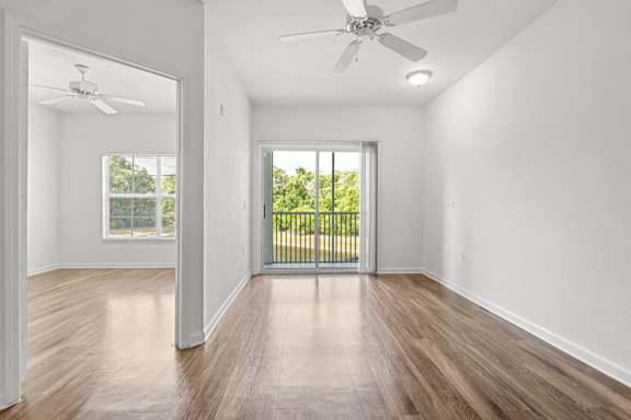 A room with a ceiling fan and sliding glass doors.