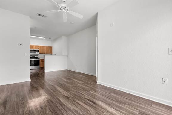 A room with a ceiling fan and wooden flooring.