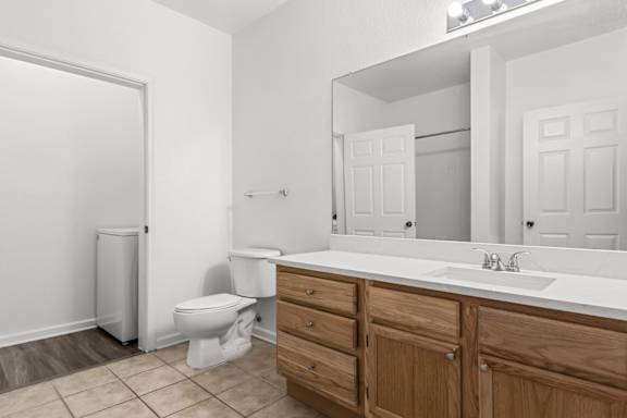 A white bathroom with a toilet, sink, and mirror.