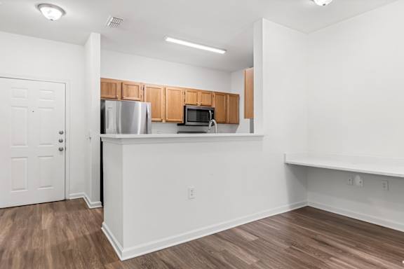 A kitchen with white walls and wooden cabinets.