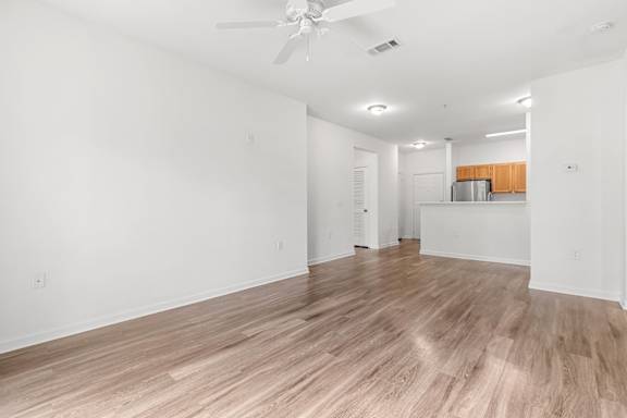 A room with a ceiling fan and wooden flooring.