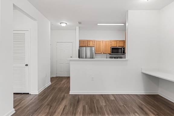 A kitchen with white walls and wooden floors.
