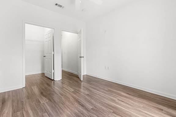 A room with white walls and wood flooring with two open doors.