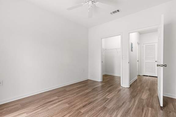 A room with a ceiling fan and wooden flooring.