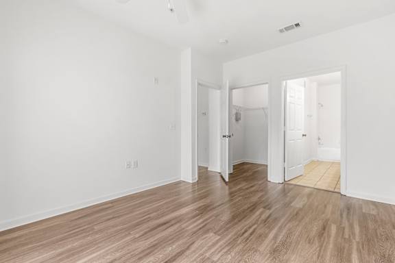 A room with white walls and wooden flooring with three doors.