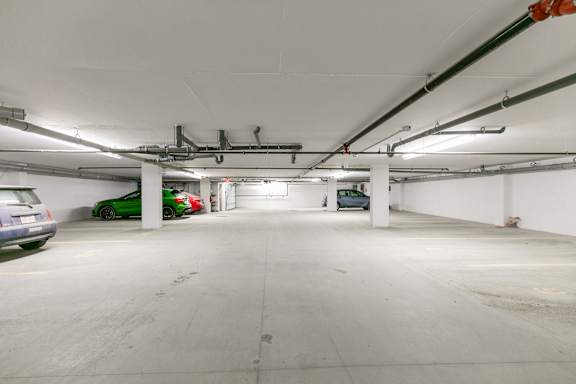 A spacious, empty parking garage with a concrete floor and white walls.
