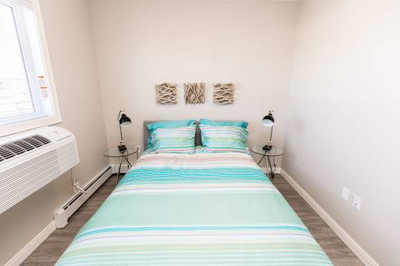 A bedroom with a bed, two lamps, and a window.