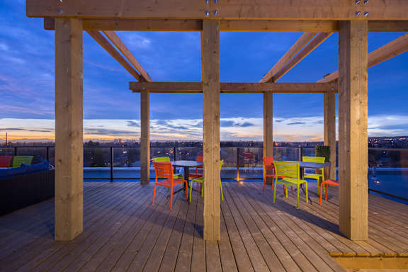 A wooden deck with a table and chairs overlooking a cityscape at dusk.