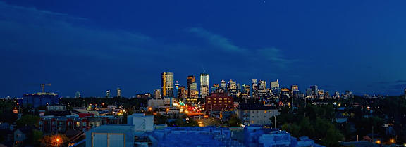 A city skyline at night with buildings lit up.