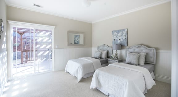 two beds in a bedroom with a sliding glass door