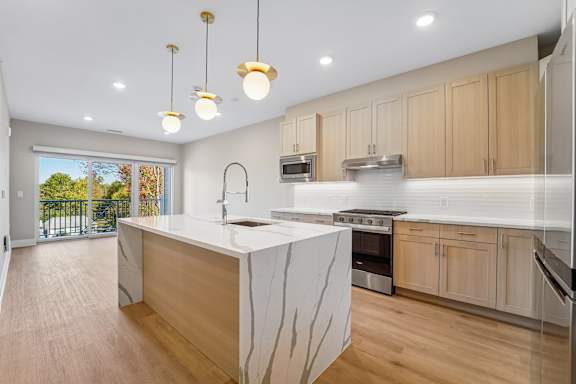 A modern kitchen with wooden cabinets and a marble island.