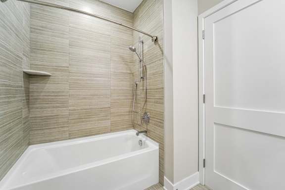 A white bathtub with a shower head and hand held shower.