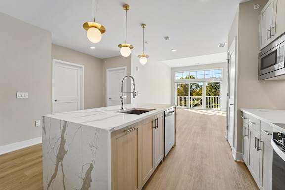 A kitchen with a marble island and wooden floors.