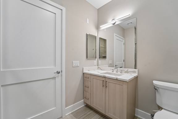 A white bathroom with a sink, mirror, and toilet.