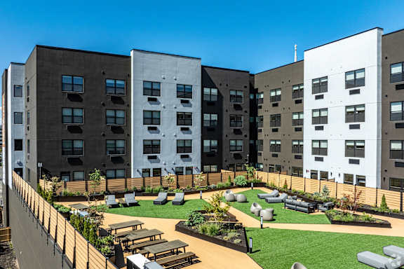 A modern apartment complex with a landscaped courtyard in the foreground.