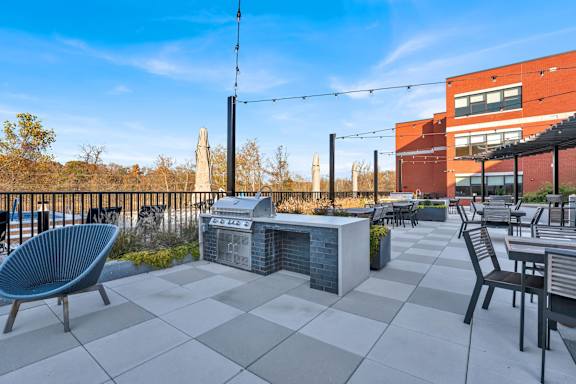 A patio with a blue chair, a table, and a fireplace.