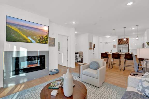 A modern living room with a fireplace and a large TV on the wall.