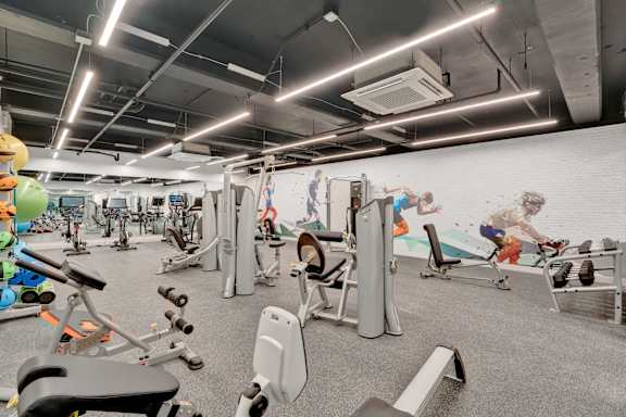 A gym with a variety of exercise equipment and a mural on the wall.
