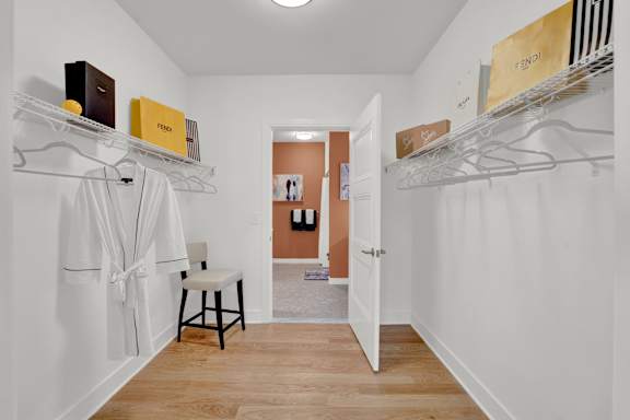 A white room with a chair and a white robe hanging on a rack.