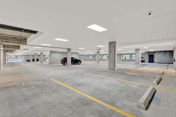 A large, empty parking garage with concrete pillars and yellow lines on the ground.