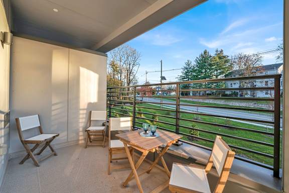 A balcony with a table and chairs overlooking a green field.