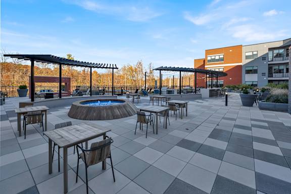 A patio with a fire pit and chairs.