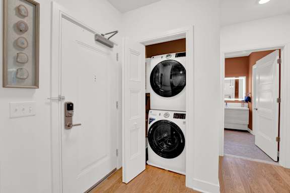 A white door with a black handle is open to reveal a white washing machine.