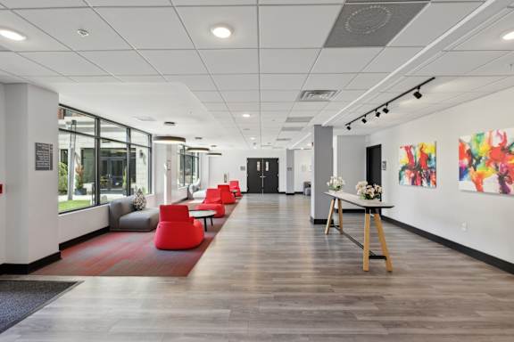 A long hallway with a red rug and chairs on the left side.