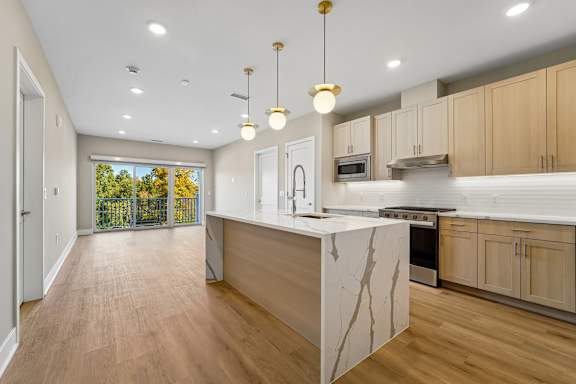 A kitchen with a marble island and wooden floors.