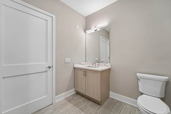 A bathroom with a toilet, sink, and mirror.