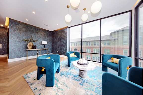 A blue chair is in the middle of a room with a table and a plant.