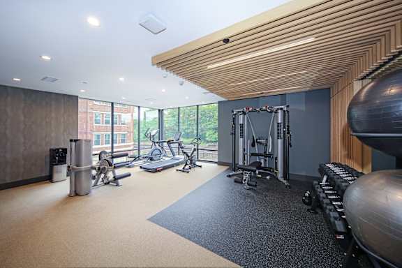 A gym with a variety of equipment including a treadmill, weights, and a balance ball.