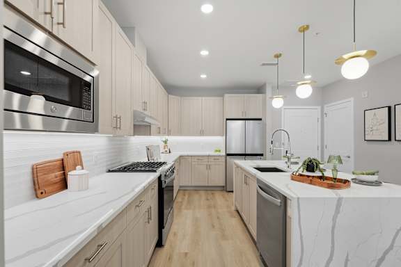 A modern kitchen with a marble countertop and stainless steel appliances.