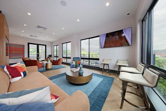 A living room with a large couch and a flat screen TV mounted on the wall.