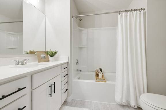 A white bathroom with a toilet, sink, and bathtub.