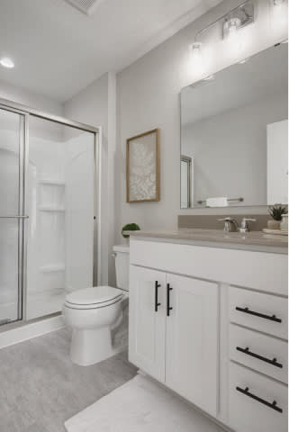 A white bathroom with a toilet, sink, and shower.