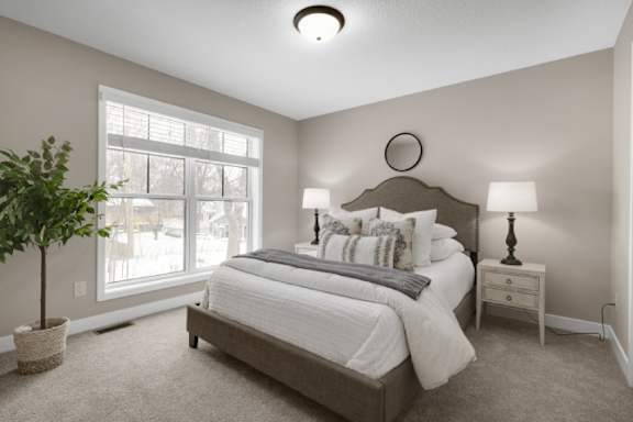 A bedroom with a large bed, a nightstand, and a potted plant.