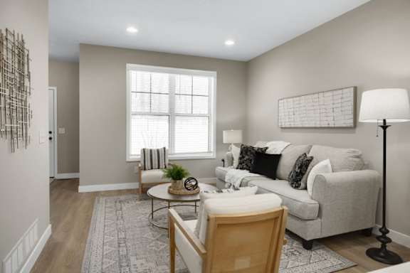 A living room with a grey couch, a wooden table, and a lamp.