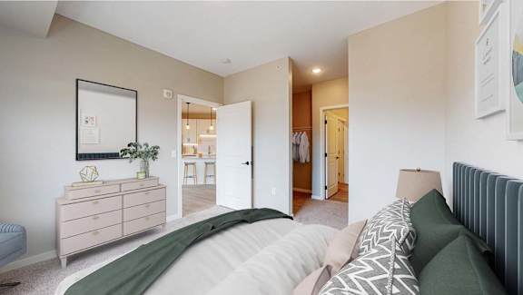 A bedroom with a large bed and a dresser with a mirror above it.