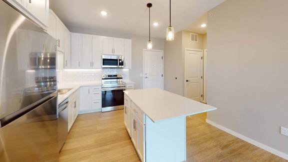 A modern kitchen with a white island and stainless steel appliances.